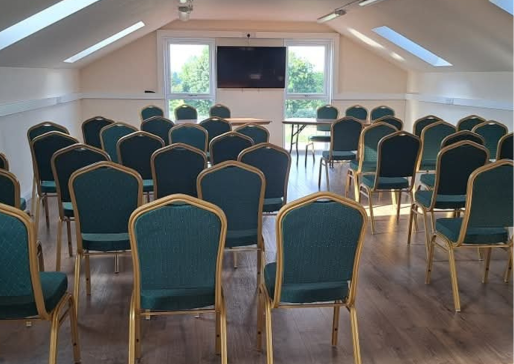 learning loft in speaker layout. head table with green chairs and screen, facing rows of green conference chairs